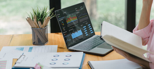 A businesswoman or accountant using laptop to analyze financial investments and business and marketing growth on a data graph. The concepts of accounting, economics, and commercial analysis.