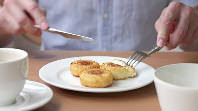 Footage Of Breakfast. A Man Is Eating Cottage Cheese Fritters, Syrniki And Drinking Coffee.