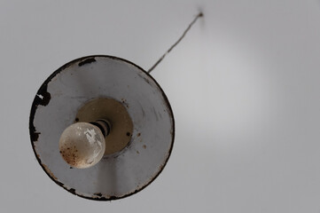 Dirty old lampshade with lightbulb covered in fly excreta