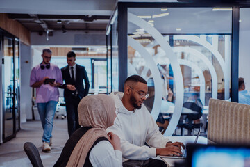 In a modern office setting, an African American businessman and his Muslim colleague, wearing a hijab, engage in collaborative discussions, tackling various business tasks and solving problems