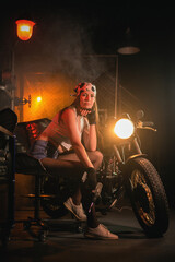 Plakat Girl with the repair tool near the old motorbike in the garage concept.