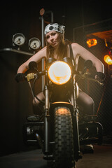 Obraz na płótnie Canvas Girl motorbiker in the bandana and black top posing on the old retro motorbike.