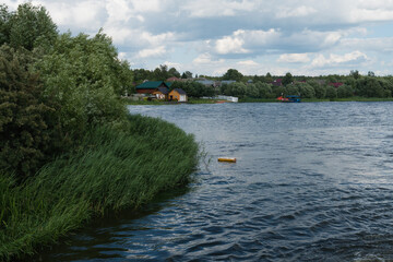 Kalyazin, Russia, July 3, 2023. River landscape with a green island and a village view.