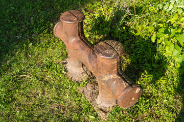 Vintage cast iron device for fixing ropes on a green lawn.