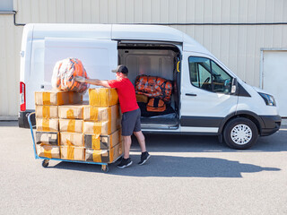 Loading goods into minivan. Man is loading boxes into car. Transport company specialist. Guy is...