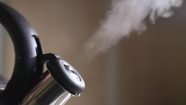Hot steam comes out of the kettle on the stove. Slow motion