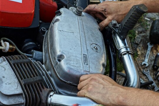 part of a closed old retro heavy powerful engine in an aluminum crankcase with an exhaust pipe and a winding lever from a red vintage Java motorcycle on the street
