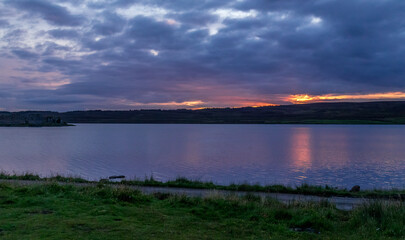 Sunset over Lochindorb and Lochindorb castle with reflection on the water of the loch