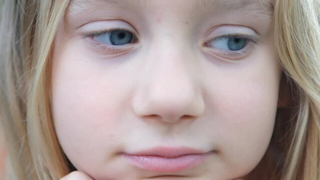 Video portrait of a blond child looking at the camera and laughing. Happy child of seven years smiling.