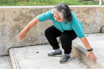 Asian elderly woman trying hard to get up because of a knee injury from arthritis of the knee. to...