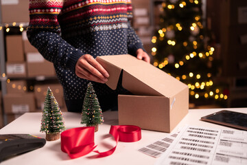 Woman online store small business owner seller packing package post shipping box on Christmas Eve....