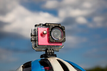 Action camera on a bicycle helmet against a blue sky background.