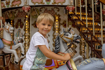 Obraz na płótnie Canvas Children, boys, going on Merry Go Round, kids play on carousel in the summer