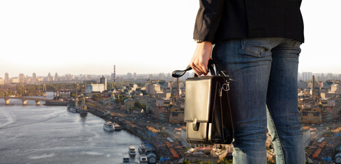 Fototapeta na wymiar A businessman with a briefcase stands against the backdrop of the big city.