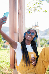 Young man in yellow dungarees taking a selfie outdoors on a sunny day. Concept: lifestyle, technology, smartphone