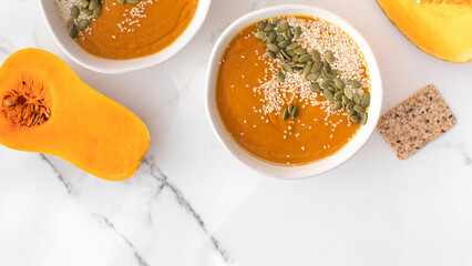 Plates with pumpkin soup puree, pumpkin and sesame seeds. Autumn menu. 