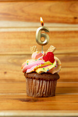 Golden birthday candle on wooden background - Birthday cupcake with numbered candle