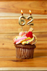 Golden birthday candle on wooden background - Birthday cupcake with numbered candle