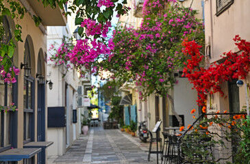 Restaurant and buildings in the narrow streets of Nafplion town with Bougainvillea flowers