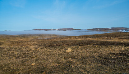 Beautiful tundra landscape with dry grass, some snow and fog in the valleys