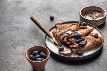 Chocolate crepes with blueberry and chocolate paste on brown textured background rustic style with...