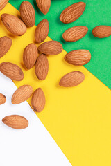 Almonds on a colorful background. Food pattern. Green, yellow and white backdrop.