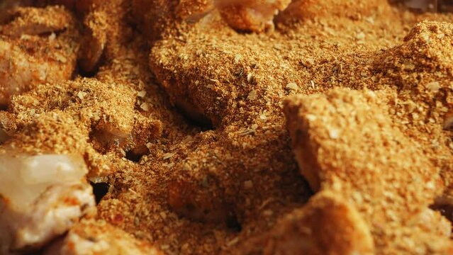 Pieces of chicken fried in a cast-iron skillet in oil with onions sprinkled with spices