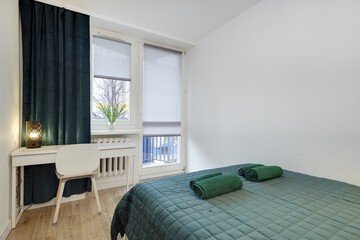 Jasna sypialnia z zielonym łózkiem i białym biurkiem do pracy