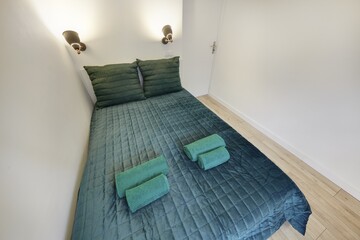 Jasna sypialnia z zielonym łózkiem i białym biurkiem do pracy - obrazy, fototapety, plakaty