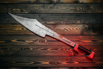 Ancient Spartan sword on the wooden table background concept. Top view.
