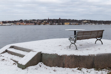 Slightly snowy metal bench overlooking the bay of Stockholm