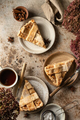 Fototapeta na wymiar Three plates with traditional apple pie pieces served for an autumn cozy tea party. Rustic stil life, brown textured background. Autumn seasonal food concept, top view