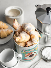 Homemade fresh croissants bagels in tin box with coffee for breakfast on white background. Cozy morning breakfast concept