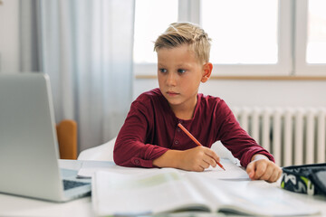 Cute Caucasian boy doing his homework.