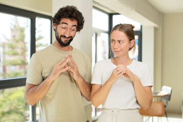 young adult couple feeling proud, mischievous and arrogant while scheming an evil plan or thinking...
