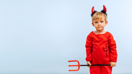 Happy cheerful boy in devil costume with trident on blue background