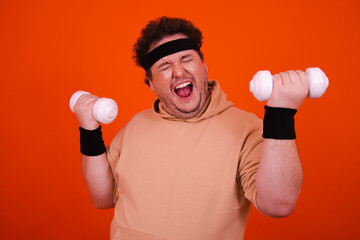 Funny fat man in the gym doing fitness and eating donuts.