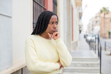 Fototapeta premium afro pretty black woman feeling confused or doubting, concentrating on an idea, thinking hard, looking to copy space on side