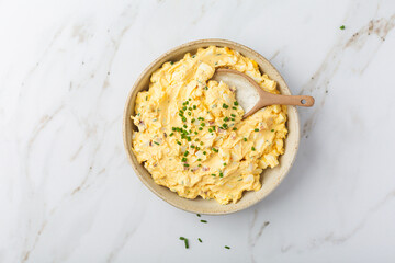 Homemade egg spread with onion, bacon and chives on marble background