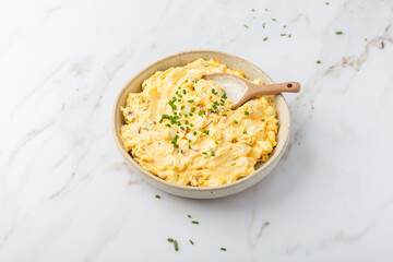 Homemade egg spread with onion, bacon and chives on marble background