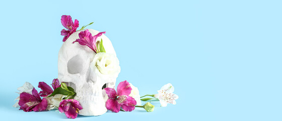 Human skull with beautiful alstroemeria flowers on light blue background with space for text
