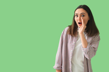 Shocked young woman on green background