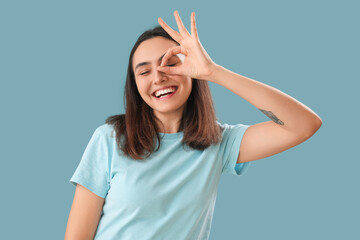 Young woman showing OK on blue background