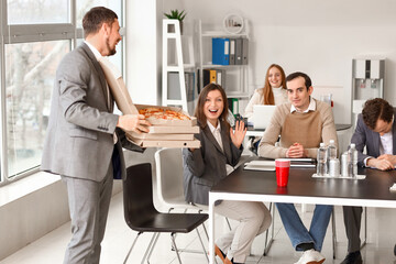 Young man with tasty pizza for his colleagues in office