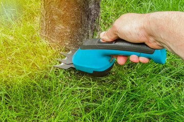 cordless handheld trimmer for lawn mowing in hard to reach places and around trees bushes