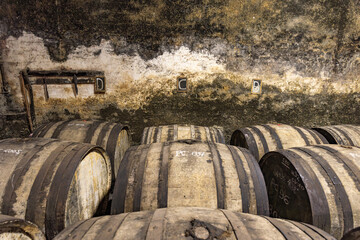 Obraz premium Old barrels for aging cognac in French cellar lined along weathered wall