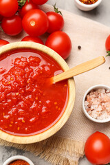 Bowl with tasty tomato sauce and fresh vegetables on grunge background, closeup