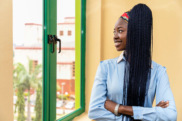 confident woman standing in front of a window with her arms crossed