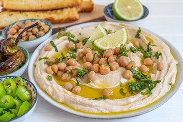 Chickpeas, fresh lime and mint over freshly prepared hummus in ceramic plate.