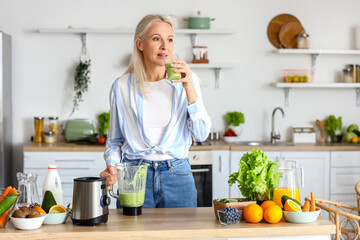 Mature woman with glass of healthy smoothie in kitchen